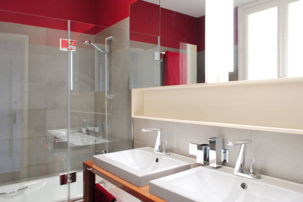 Reforma de interiorismo de un piso en Barcelona diseñado por el estudio de diseño internacional Manuel Torres Design donde se ve el baño decorado en tonos blancos y rojos