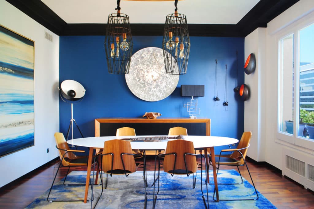 Reforma de interiorismo de un piso en Barcelona diseñado por el estudio de diseño internacional Manuel Torres Design donde se ve un comedor decorado en tonos azules y blanco con mesa de madera
